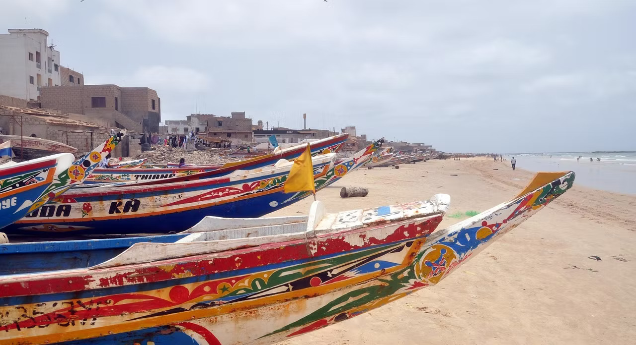 Colorful traditional pirogues on the beach in Dakar, Senegal — community fishing livelihoods